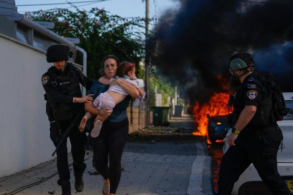 Police evacuate a woman and child from the site of a rocket attack in Israel during Saturday's violence.